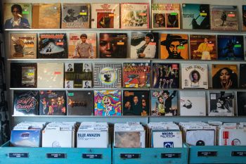 Vinyl record shop with a wall of vinyl record covers displayed and boxes of records below for people to browse
