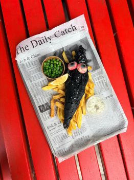 A photo of fish and chips with a Halloween twist - black batter on the cod and bloodshot eyes