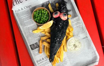 A photo of fish and chips with a Halloween twist - black batter on the cod and bloodshot eyes