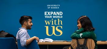 Two students face each other against a blue wall