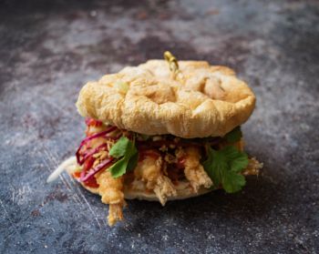 A photo of a sandwich with crispy fried prawns and garnishes