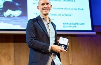 Professor Anil Seth accepts an award on stage