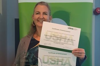 Katie Bennett with the team's award and two certificates at the ceremony