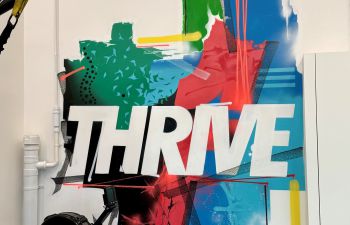 A photo of a wall graphic that says 'Thrive' in Active Arches workout space on the University of Sussex campus