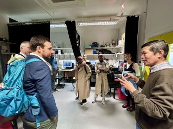 A group of visitors and academics discussing the equipment available to researchers in the Sussex Genome Centre