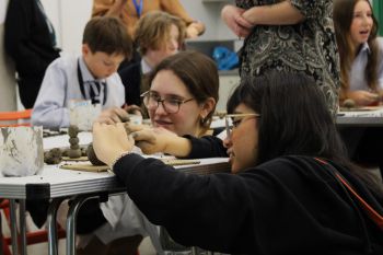 A University of Sussex student helping a Year 9 student to make a clay sculpture