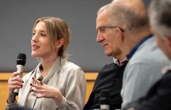 Dr Hannah Richter speaking into a microphone next to Professor Paul Taggart