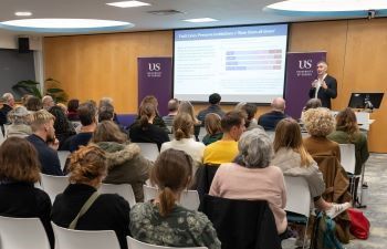 Luke Tryl at lectern speaking to an audience