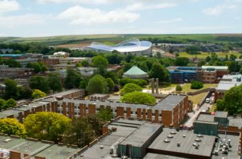 An image of two university buildings behind a University of Sussex sign
