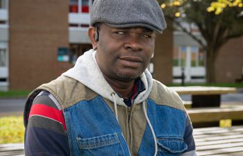 Michael Fadeyi sitting outside on a bench with a beautiful tree in the background.