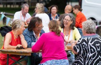A small group of people sitting at a picnic table smiling and laughing