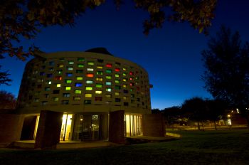 The Meeting House at night illuminated with its multi coloured stained glass windows.
