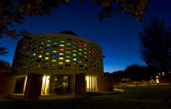 The Meeting House at night illuminated with its multi coloured stained glass windows.
