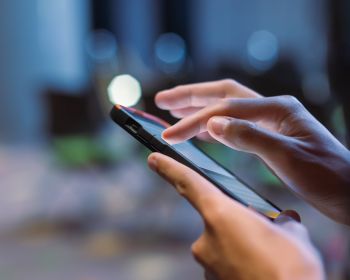 A photo of hands holding and scrolling on a smartphone