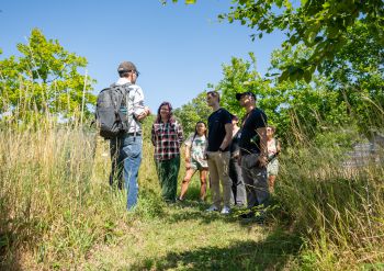 Tutor teaching students outside in the South Downs National Park surrounded by greenery, nature and blue skies