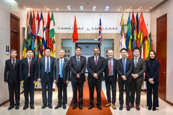 Group of 9 men and one woman at UIBE standing in front of international flags, smiling