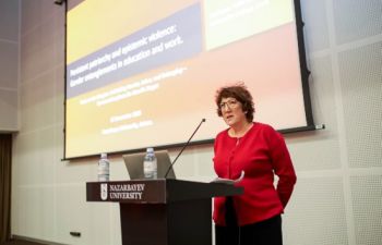 photo of mairead stood behind a podium with a powerpoint projected onto a screen behind her