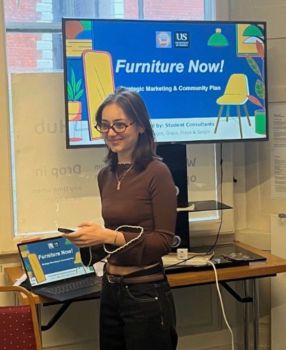 Image of Grace standing in front of a presentation screen