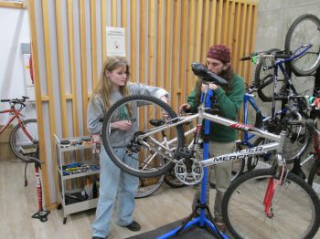 Maintenance session in progress with someone learning how to fix a bike from a trained mechanic