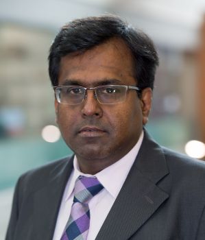 Profile of man with dark hair and glasses wearing a business suit