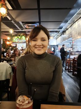 Coral Buckland seated at a table in a restaurant and smiling at the camera