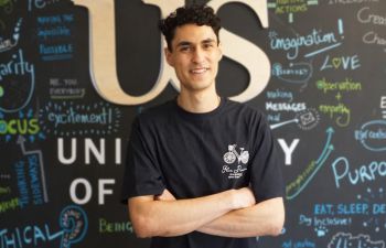 Christopher El-Nahhas standing, arms folded and smiling at the camera