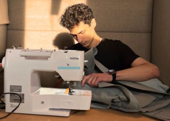 Christopher El-Nahhas sitting with a sewing machine and sewing one of his Ostopacks