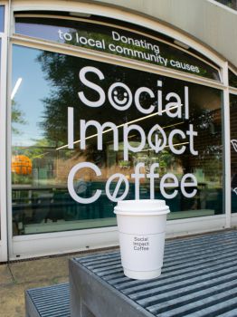 A photo of a Social Impact Coffee cup outside of Arts Piazza Café