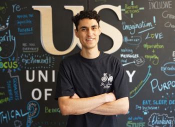 Headshot of Christopher El-Nahhas standing in front of a blackboard