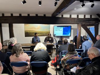 Delegates seated at the conference in Bull House, listening to two speakers