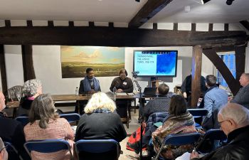 Delegates seated at the conference in Bull House, listening to two speakers