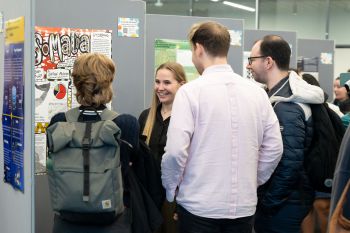 People looking at JRA poster exhibition and smiling.
