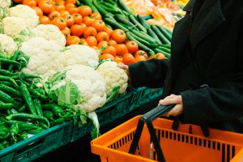 person with a shopping basket choosing vegatables