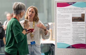 Two people stand in conversation at the 2025 Sussex Education Festival, in front of a research poster titled “Understanding the student experience of Black, Asian and Minority Ethnic students on campus.”