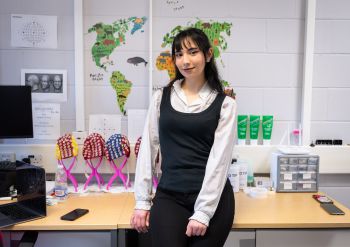 Farah in the Human Psychophysiology Lab in front of a desk with brain scanning equipment