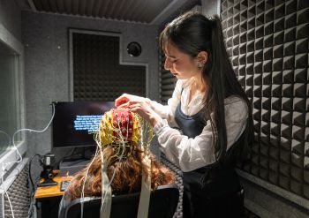 Farah in the Human Psychophysiology Lab using brain scanning equipment on a participant