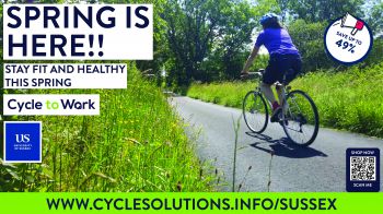 Person riding on bike through grass, text on left reads 'Spring is here! Stay fit and healthy this Spring. Cycle to work'.