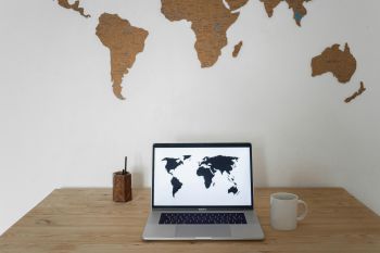 Photo of a laptop, displaying a map of the world, on a desk