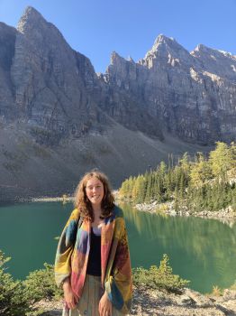 Nancy standing in front of mountains, trees and a lake in Canada