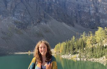 Nancy standing in front of mountains, trees and a lake in Canada