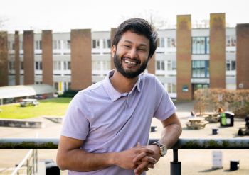 Robin Choudhary stood outside smiling with a courtyard and buildings in the background.