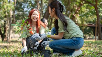 Two students plant new tree saplings