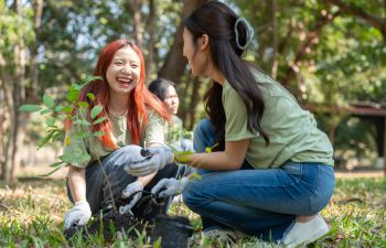 Two students plant new tree saplings