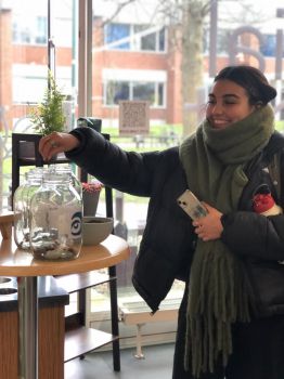A photo of someone voting for a charity but placing coffee beans in a jar