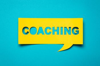 The word 'Coaching' on a bright yellow and blue background