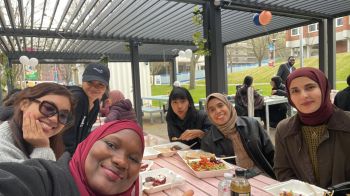 Six women smile around a table with food