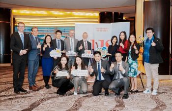 Group of academics and students in China smiling at camera with thumbs up