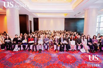large group of seated faculty and students in a room with a red carpet in China