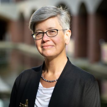 Head and shoulders image of University of Sussex Vice Chancellor Sasha Roseneil who has short grey hair and is wearing glasses and a light-coloured shirt