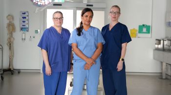 A photo of Prof Jeanette Rotchell (Lincoln), Liz Bonnin and Prof Claire Smith (BSMS) in blue scrubs in the BSMS dissection rooms on the Sussex campus